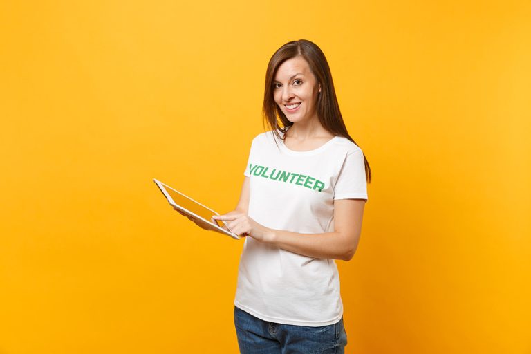 Happy woman in white t-shirt that says volunteer