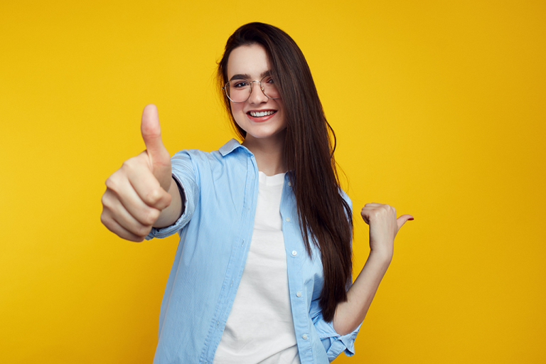 Happy young woman giving a thumbs up sign