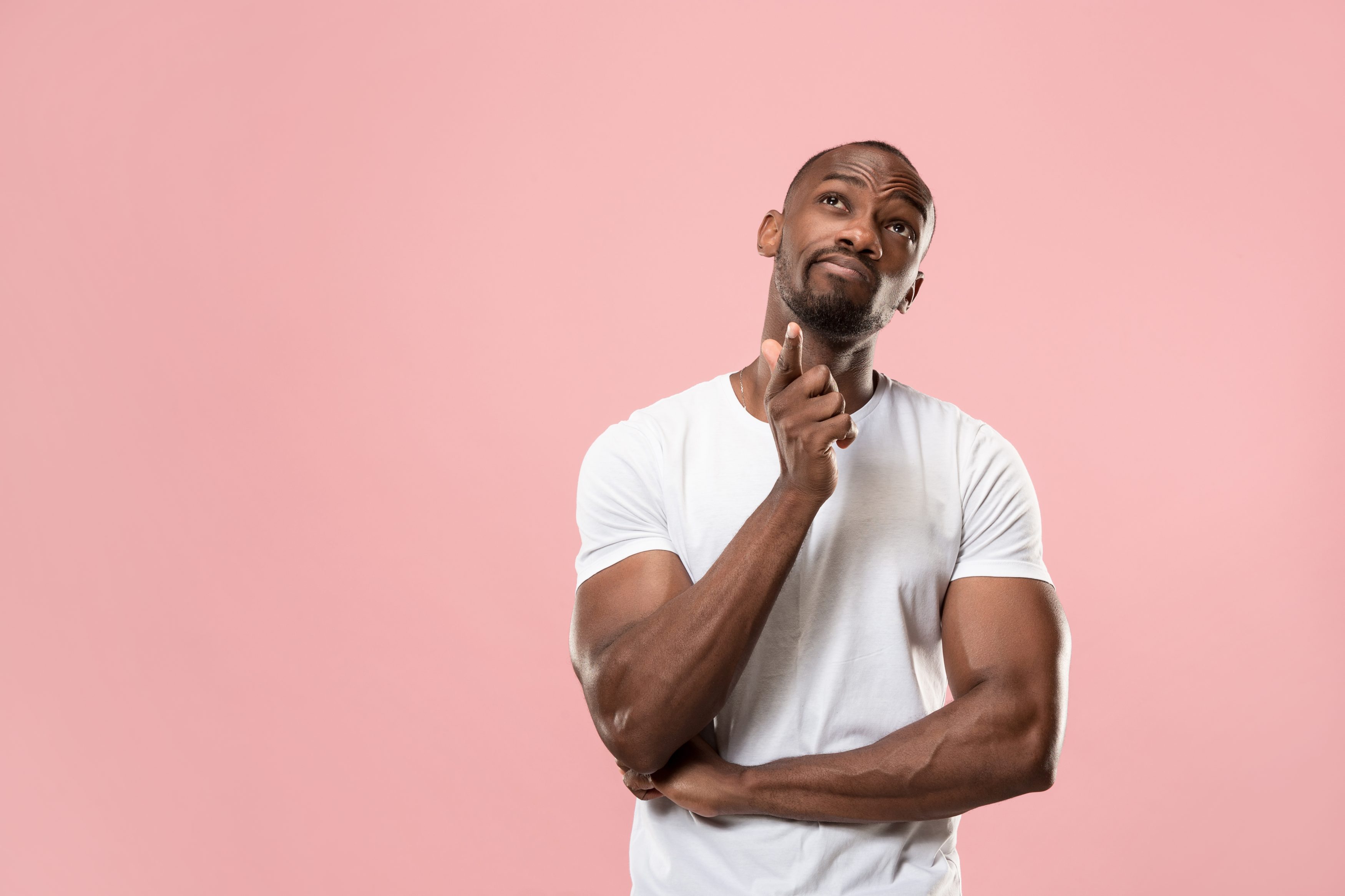 Gentleman thinking wearing a white t-shirt against a pink background.